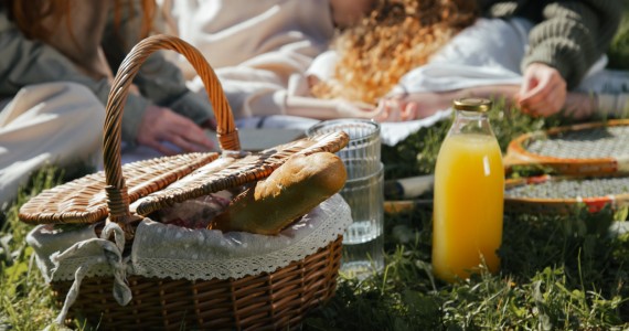 A picnic basket with bread and orange juice.