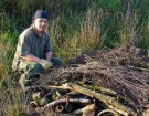 Two men kneel alongside wildlife home made from natural materials